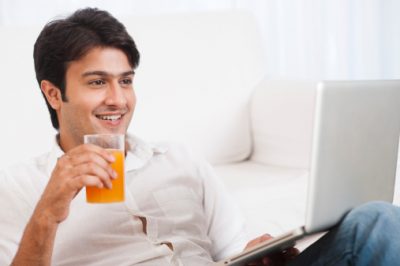 Man using a laptop with a glass of juice